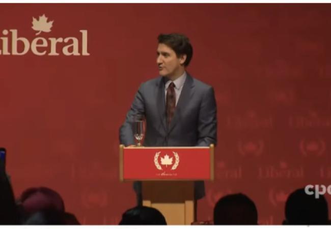 Canada's Prime Minister Trudeau standing at a dias emblazoned with a communist symbol