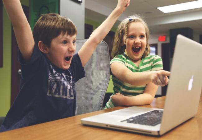 Children cheering at what's displayed on a laptop
