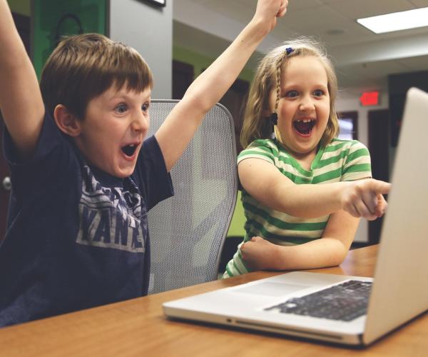 Children cheering at what's displayed on a laptop