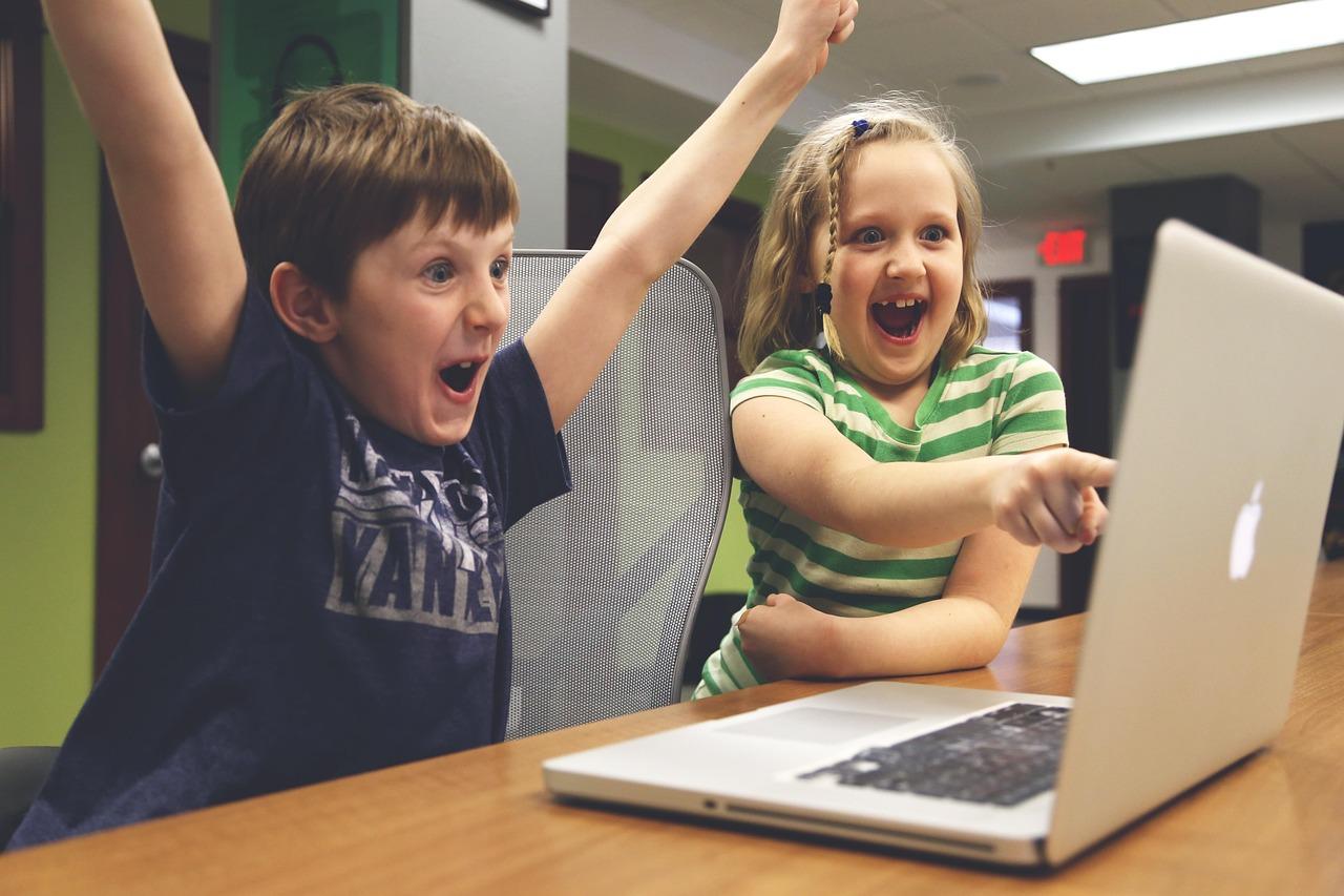 Children cheering at what's displayed on a laptop