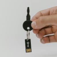 Hand holding a key, with a computer chip suspended from the key