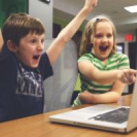 Children cheering at what's displayed on a laptop